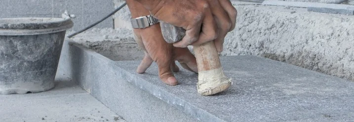 Natursteinplatte wird auf Treppenstufe befestigt.